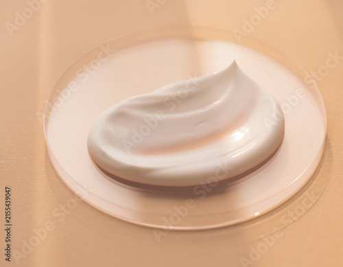 Luxurious white cosmetic cream, rich and smooth in texture, gracefully swirled on a transparent glass plate, perfect for beauty, skincare, and product display concepts