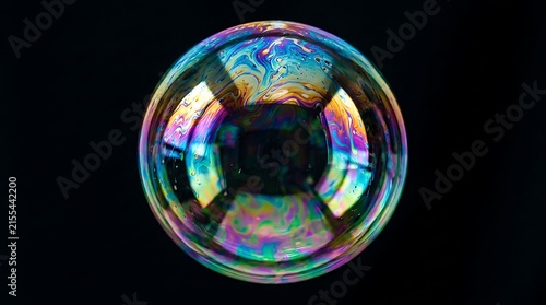 Large iridescent soap bubble floating against a solid black background, showing swirling rainbow colors on surface