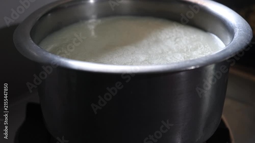 Fresh milk boiling in a stainless steel pot on a kitchen stove, showing a common traditional cooking process in an Indian household.