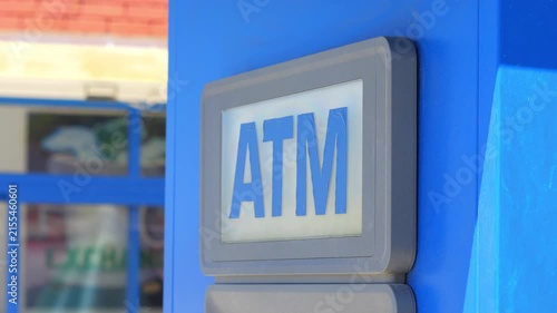 A close-up shot of an ATM sign in a public space, highlighting the logo on a blue background in 4K slow motion 60fps