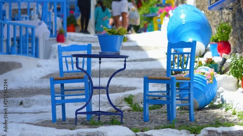 Charming Greek outdoor seating with blue chairs and white steps in a peaceful setting in slow motion 60fps
