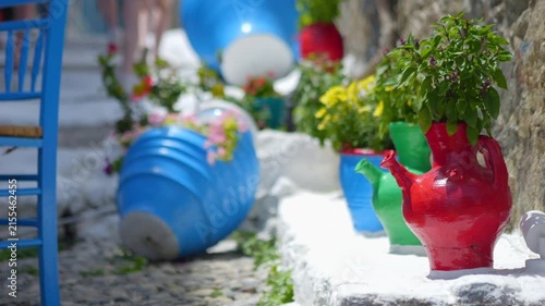 Charming Greek outdoor seating with blue chairs and white steps in a peaceful setting in slow motion 60fps