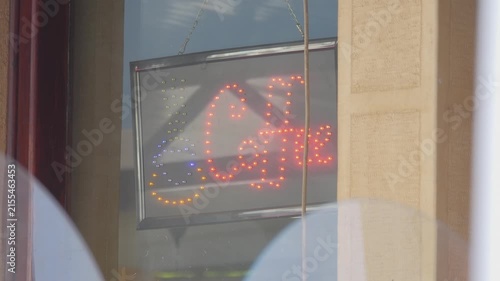A glowing red neon coffee sign in a café window in 4K slow motion 120fps