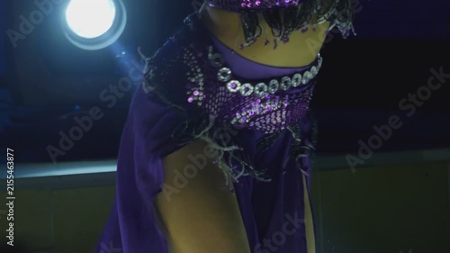 A belly dancer performing under stage lights, captured in 4K slow motion 120fps