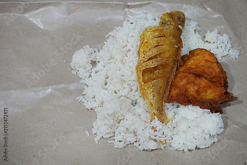 Rice on food paper liner with fish and chicken pieces. Source of carbohydrates and proteins for Asians
