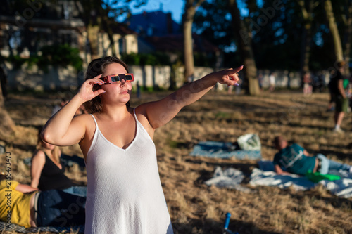 Fotografía A woman wears solar eclipse glasses and points toward the sky during a public observation event in Paris, France