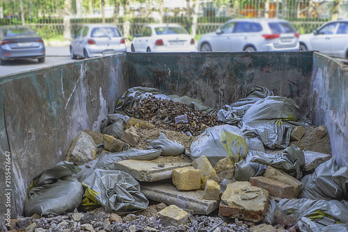 A container with construction debris by the roadside on a summer day