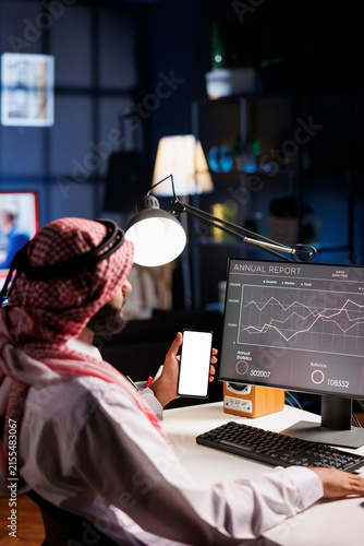 Businessman Analyzing Financial Data and Annual Report on Computer Monitor
