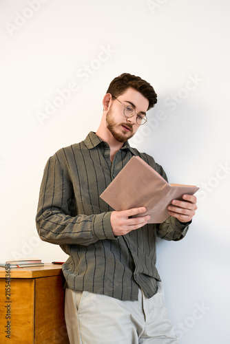Cuadro en lienzo Stylish young man reading in a modern studio with a casual yet refined look