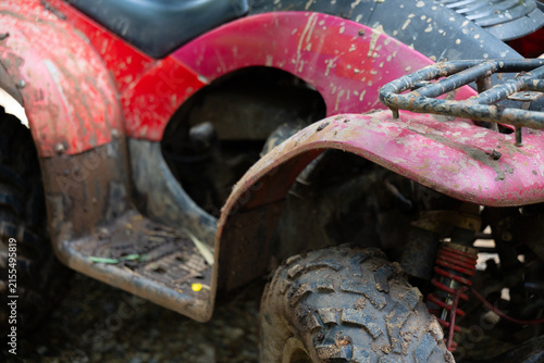Obraz na płótnie Muddy red all terrain vehicle with dirt splattered fender and knobby tire showin
