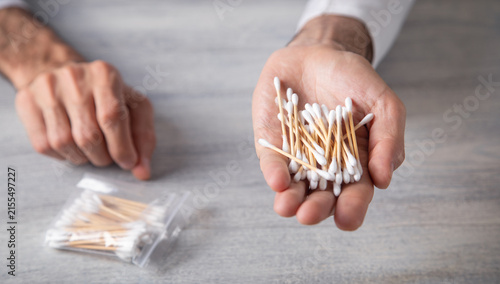 Caucasian man showing cotton bud for ear cleaning.