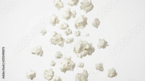 Fresh ricotta cheese dollops falling against white background
