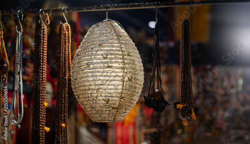 A decorated paper lantern hangs among handcrafted necklaces at a night market.