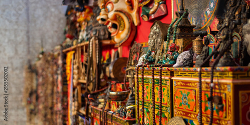A stall selling traditional Tibetan handicrafts, including traditional masks, deity statues, and colorful Buddhist rosaries.