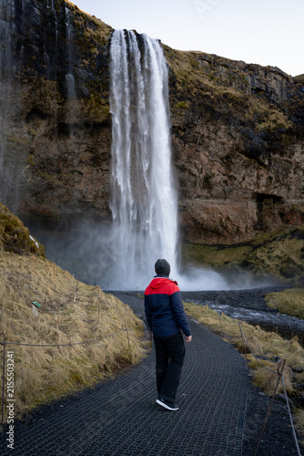 Fotografía Rear View of Man Walking Towards Seljalandsfoss Waterfall in Iceland