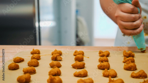 Bild auf Leinwand Vegan pumpkin tortellini being piped onto parchment paper in a professional kitc
