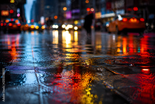 Wet urban street glows with colorful traffic lights, headlights, and neon reflections, creating a cinematic atmosphere during rainy nighttime travel.