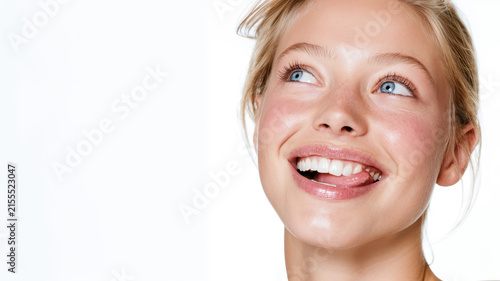 Young woman with natural beauty and radiant skin smiling, looking up while licking lips, expressing happiness, freshness, and healthy lifestyle on white background