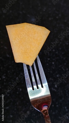 Принти на полотні A silver fork holds a small wedge-shaped slice of cheese against a dark granite surface
