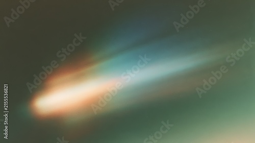 Long-exposure view of a bright comet streaking across the night sky, its colorful tail glowing with dust and ionized gas.