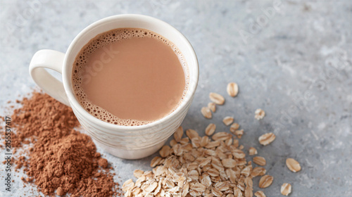 Hot chocolate drink with cocoa powder and oat flakes on gray surface