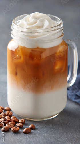Iced coffee with milk and whipped cream in glass jar with coffee beans