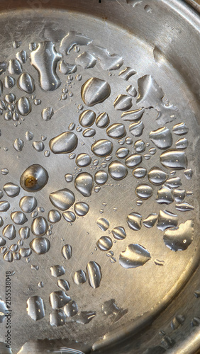 Metallic Water Droplets Macro Background. Reflective liquid beads on a brushed steel surface demonstrating physical surface tension and fluid motion.  Macro photography