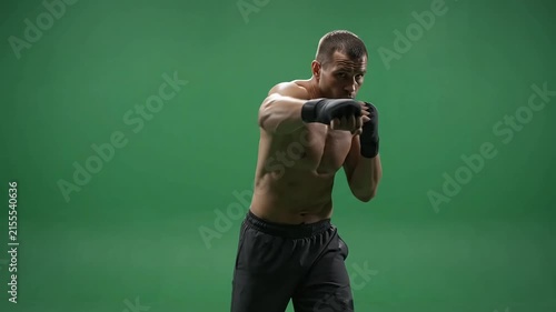 Muscular male boxer training with shadowboxing movements, striking and punching in slow motion against a clean green screen background, full body shot for compositing