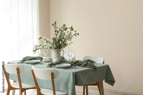 Beautiful table setting with blossoming branches, plates, glasses and fabric ...
