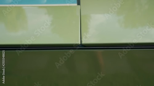 Close up of green automotive panel with reflections of trees