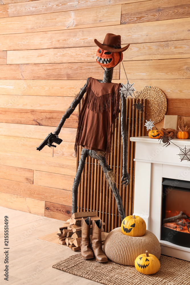 Fototapeta premium Interior of festive living room with Spooky Halloween monster and autumn decorations on fireplace
