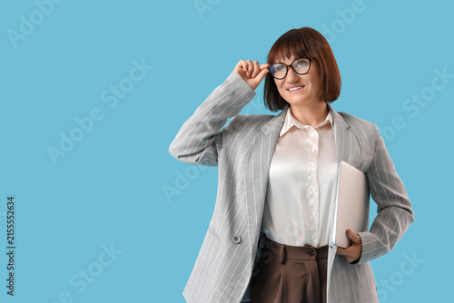 Female teacher of computer sciences with laptop on blue background