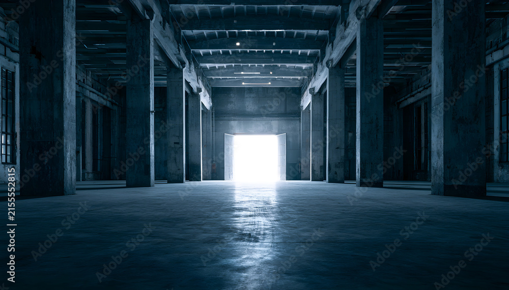 Fototapeta premium Wide empty industrial warehouse interior with concrete structure, massive pillars. Bright light shines through far exit doorway. Sombre blue tones fill cold minimalist hall space. Large vacant