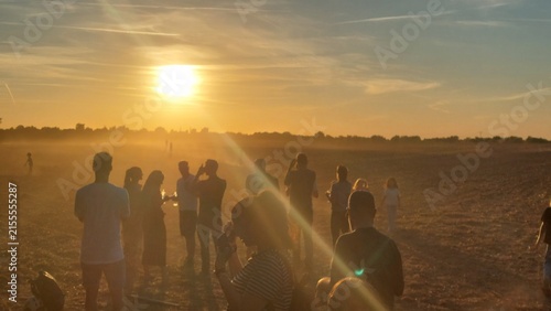 Gruppe von Zuschauern blickt auf einem staubigen Feld in den Sonnenuntergang der partiellen Sonnenfinsternis