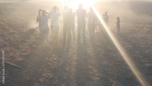 Gruppe von Zuschauern blickt auf einem staubigen Feld in den Sonnenuntergang der partiellen Sonnenfinsternis