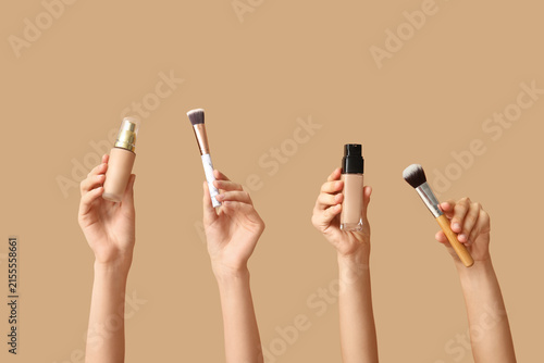 Konstfotografi Female hands with bottles of makeup foundation and brushes on brown background