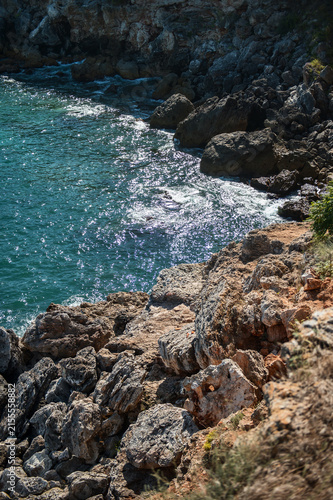 Aerial view of ocean waves crashing against rocky cliffs and large stones