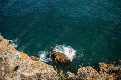 Aerial view of ocean waves crashing against rocky cliffs and large stones