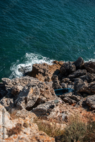 Aerial view of ocean waves crashing against rocky cliffs and large stones