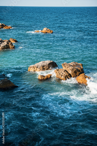 Scenic rocky coastline with turquoise sea water, cliff and rocks on a sunny day
