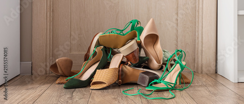 Quadro su tela Messy pile of various women's shoes on a wooden floor, fashion and disorganizati