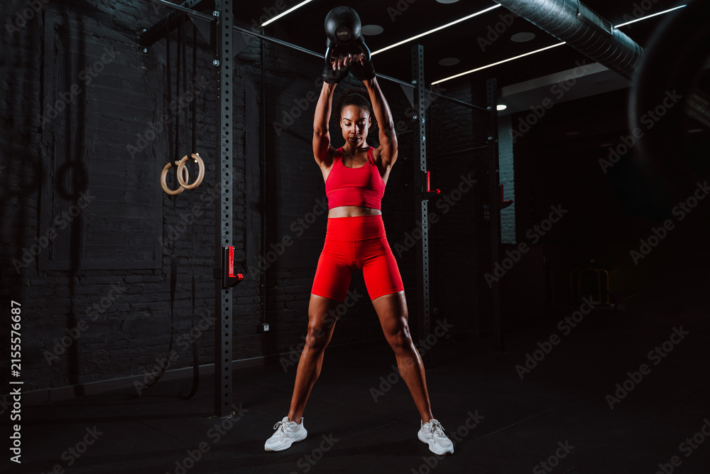 Fototapeta premium Fit young woman in red sport outfit making workout in the gym