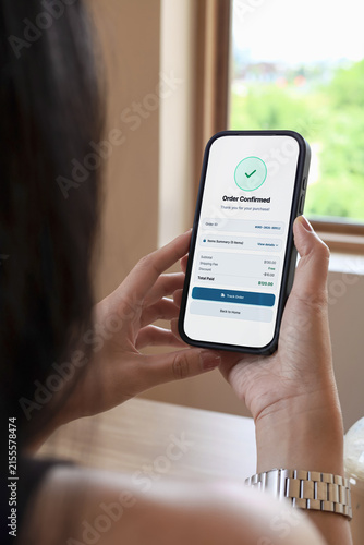 Woman holding smartphone showing order confirmed screen with check mark. Concept of online shopping, mobile payment success, and e-commerce application.