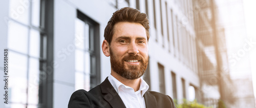 Canvas Print Confident Caucasian Male Businessman Smiling While Standing Outside Modern Office Building, With Arms Crossed, Exuding Professionalism And Success In Urban Environment, Business Concept