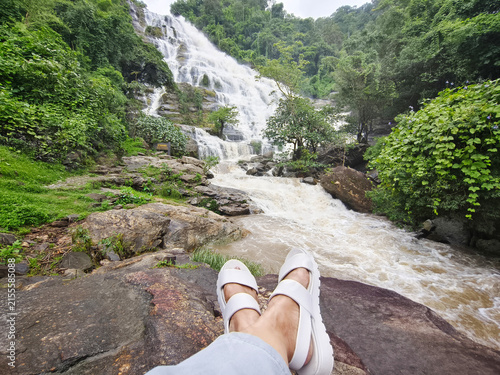 Tourist selfie feet wearing white shoes on the rock at Mae Ya waterfall, Doi Inthanon National park, Chiangmai, Thailand.