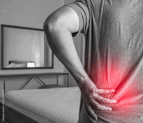 Foto Lower back pain highlighted with red glow showing patient discomfort in bedroom setting reflecting medical symptom and healthcare treatment concept