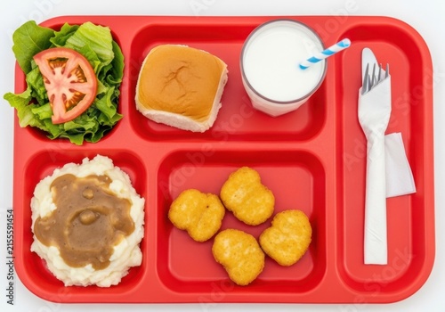 School lunch tray with chicken nuggets, mashed potatoes, salad, and milk isolated on white background
