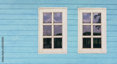 two old white windows on teal blue wood wooden wall , rustic vintage rural house home background , nostalgia concept 