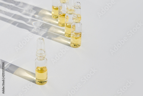 Transparent Glass Ampoules with Skin Care Serum and Natural Elements on Neutral Background