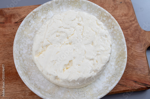 Fresh young chèvre goat cheese from France on ceramic plate. Creamy artisanal soft cheese with hite color and delicate fresh texture.